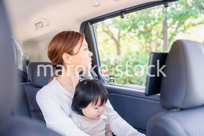 子どもと一緒にタクシーに乗って外を眺めるお母さん