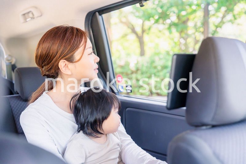子どもと一緒にタクシーに乗って外を眺めるお母さん