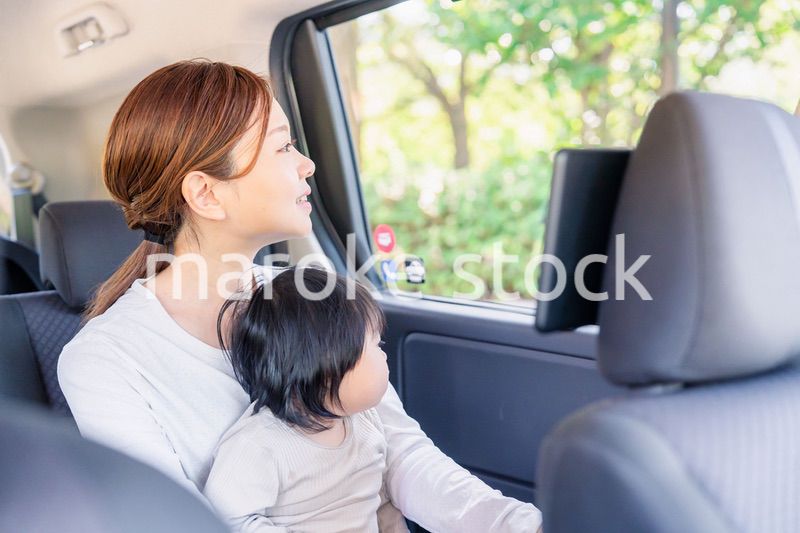 子どもと一緒にタクシーに乗って外を眺めるお母さん
