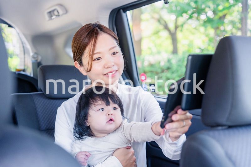 小さい子供と一緒にタクシーに乗るお母さん