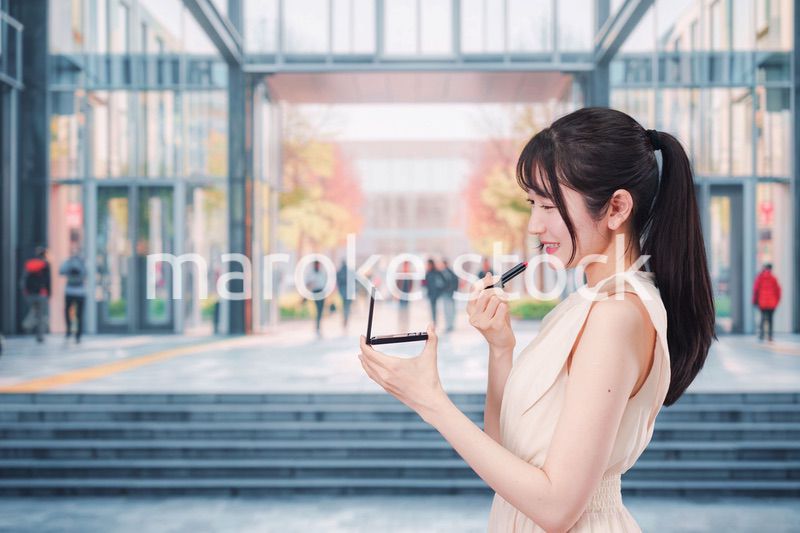 大学のキャンパスでお化粧をする大学生の女性