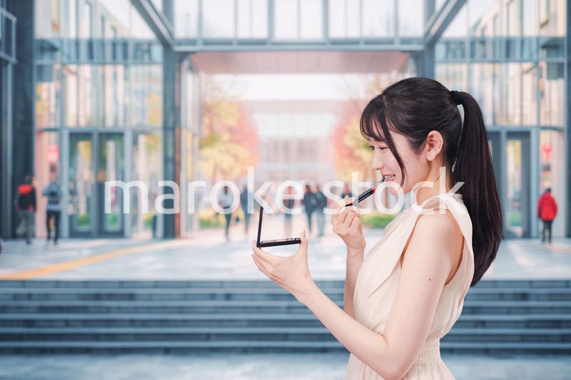 大学のキャンパスでお化粧をする大学生の女性