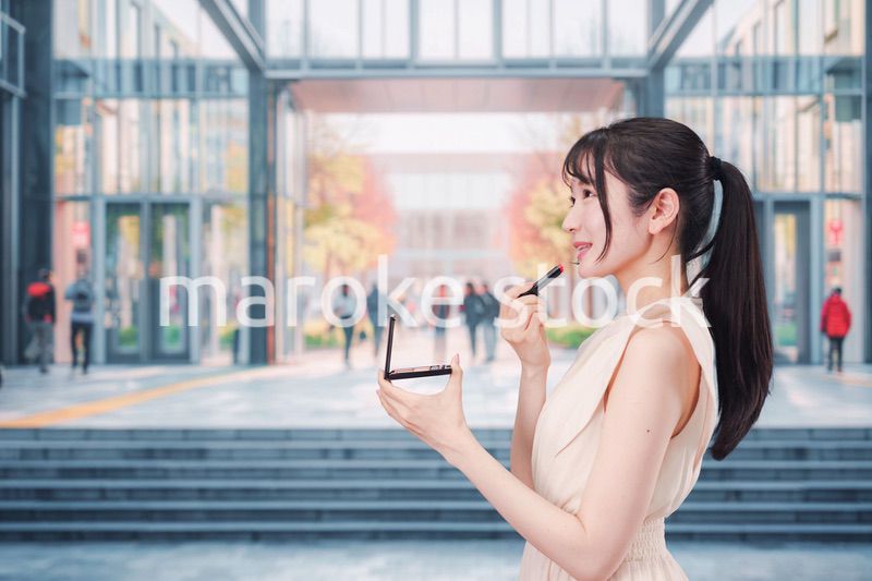 大学のキャンパスでお化粧をする大学生の女性