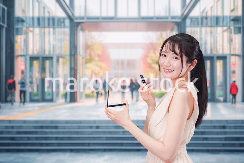 大学のキャンパスでお化粧をする大学生の女性