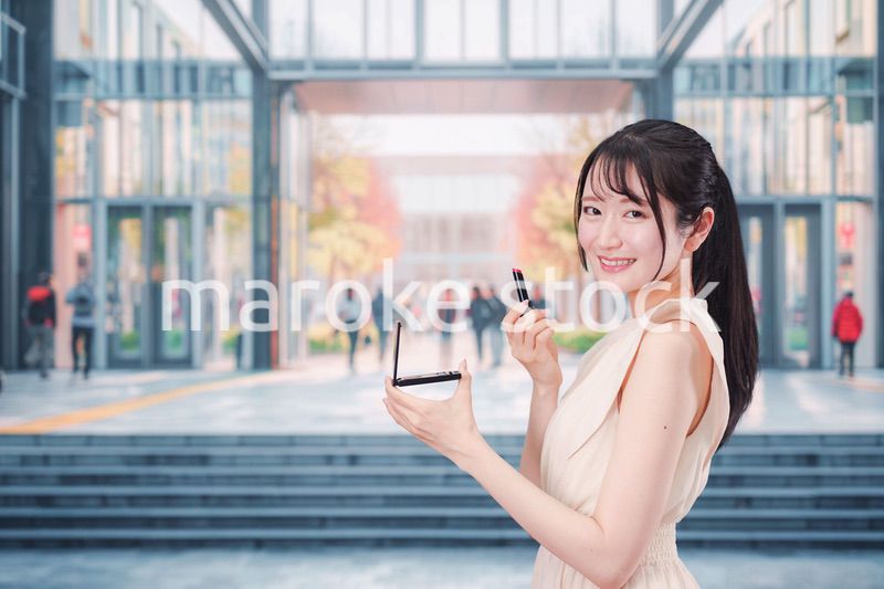 大学のキャンパスでお化粧をする大学生の女性