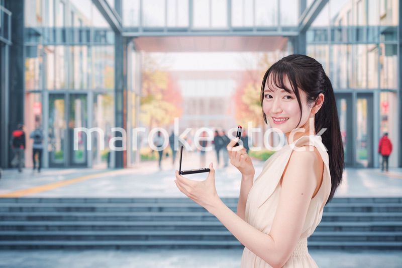 大学のキャンパスでお化粧をする大学生の女性