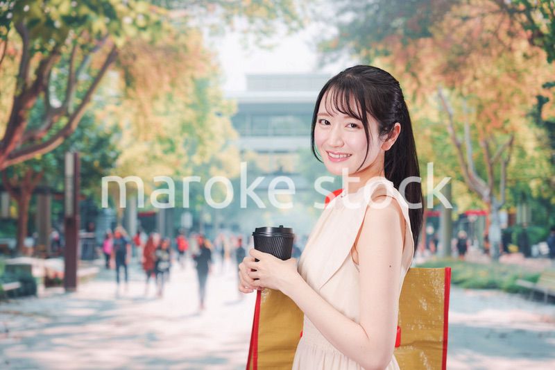 コーヒーを飲みながら外を歩く若い学生