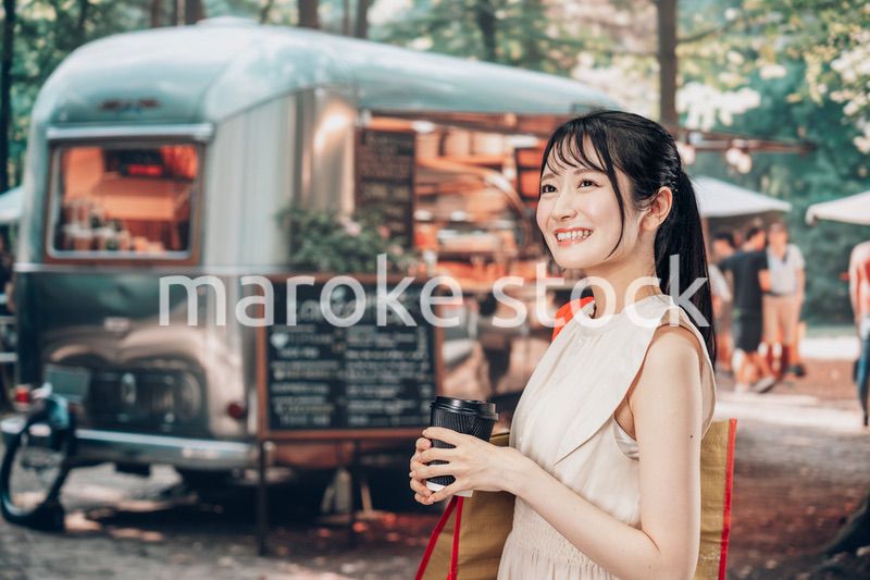 屋外のマーケットプレイスで飲食を楽しむ若い女性