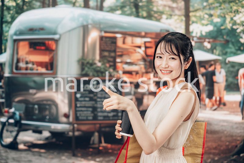 屋外のマーケットプレイスで飲食を楽しむ若い女性