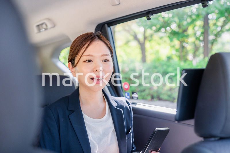 タクシーでスマホを使う若い女性ビジネスパーソン