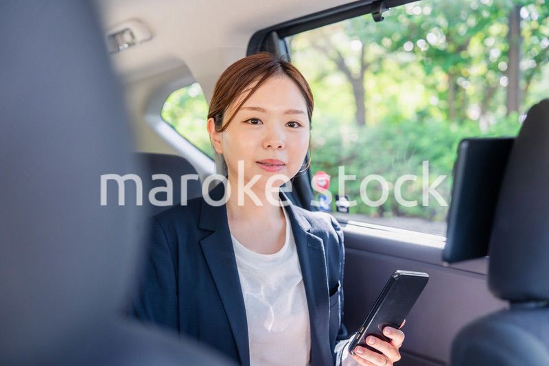 タクシーでスマホを使う若い女性ビジネスパーソン