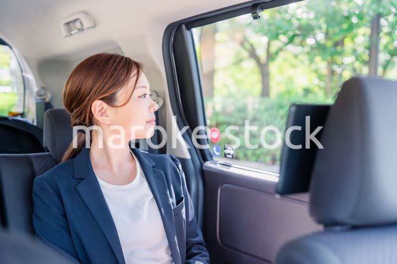 タクシーの後部座席に座るキャリアウーマン