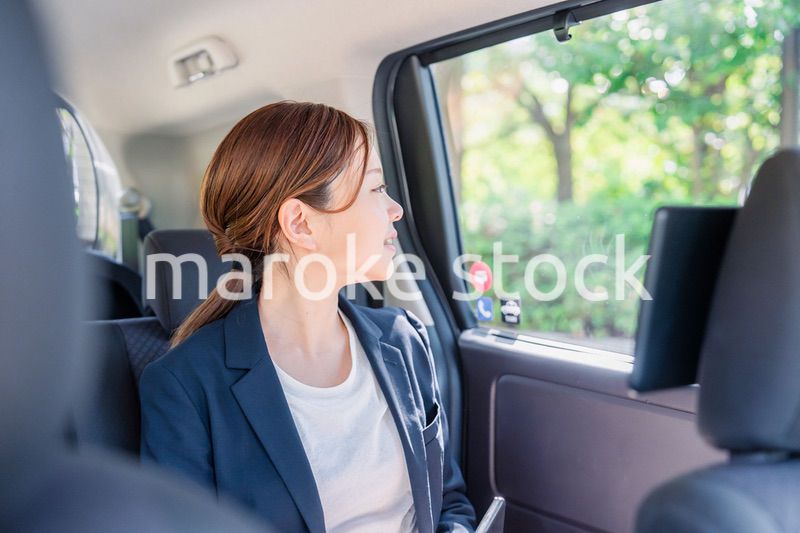 タクシーの後部座席に座るキャリアウーマン