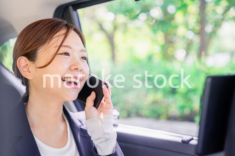 タクシーに乗って電話をする若い営業の女性