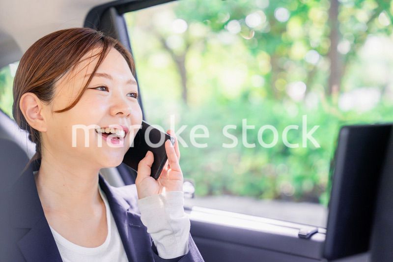タクシーに乗って電話をする若い営業の女性