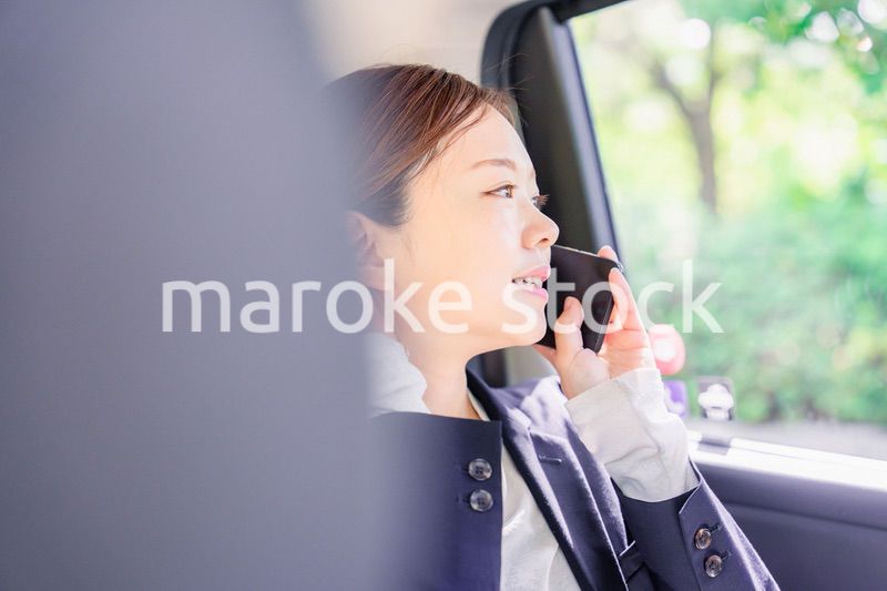 タクシーに乗って電話をする若い営業の女性