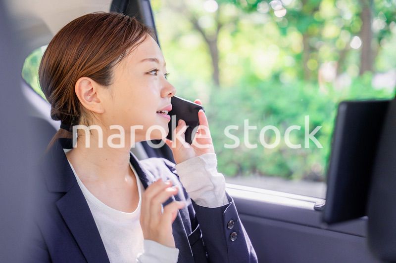 タクシーに乗って電話をする若い営業の女性