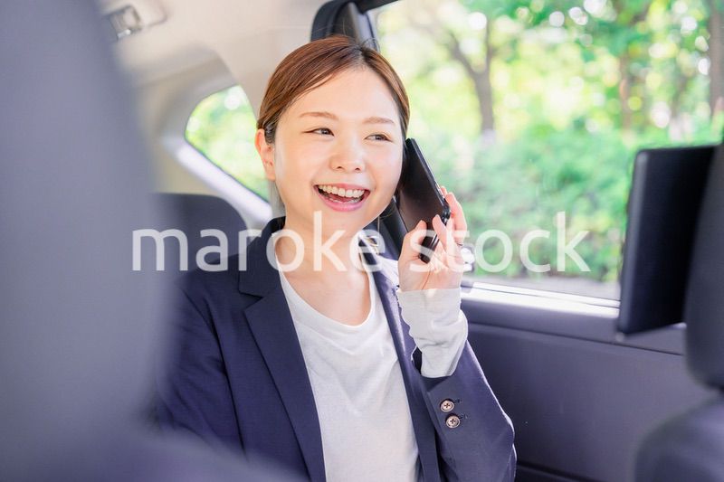 タクシーに乗って電話をする若い営業の女性