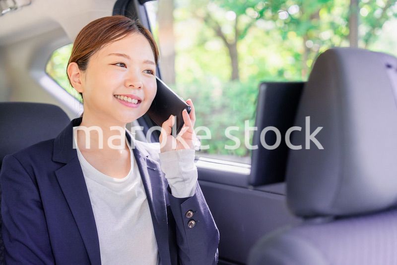 タクシーに乗って電話をする若い営業の女性