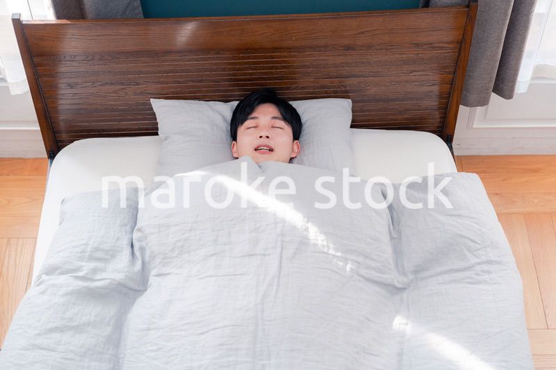 朝日が差し込む中で寝る若い男性