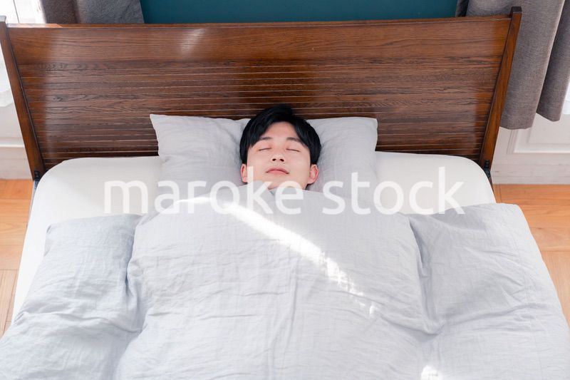 朝日が差し込む中で寝る若い男性