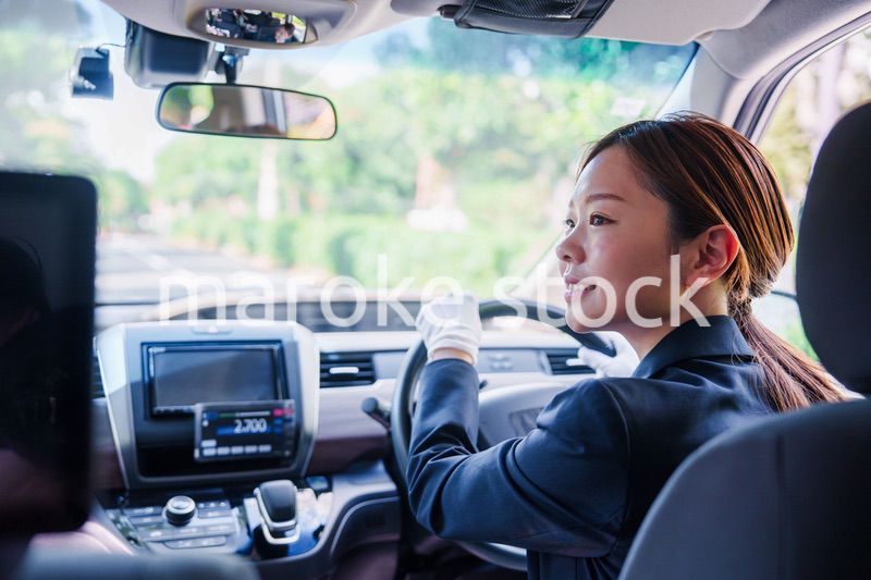 笑顔で運転をするタクシードライバーの女性