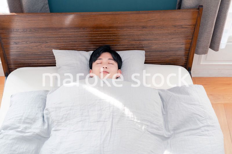 朝日が差し込む中で寝る若い男性