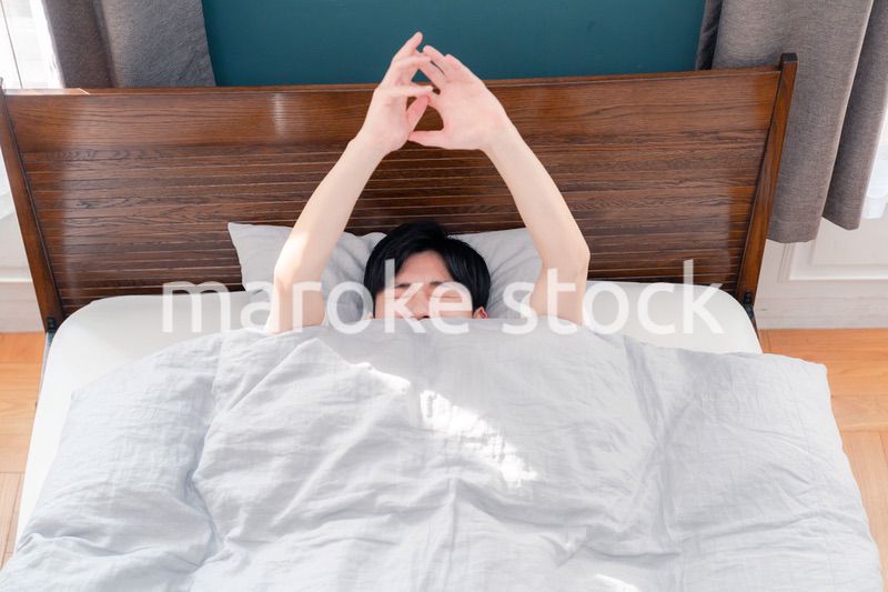 朝日が差し込む中で爽やかに目覚める若い男性