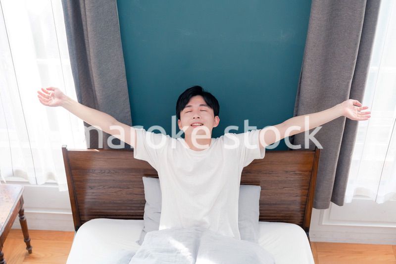 朝日が差し込む中で爽やかに目覚める若い男性