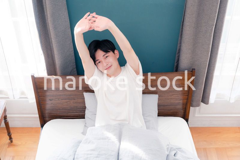 朝日が差し込む中で爽やかに目覚める若い男性