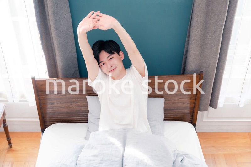 朝日が差し込む中で爽やかに目覚める若い男性