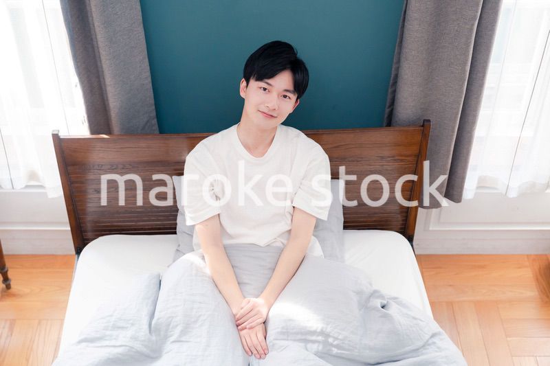 朝日が差し込む中で爽やかに目覚める若い男性