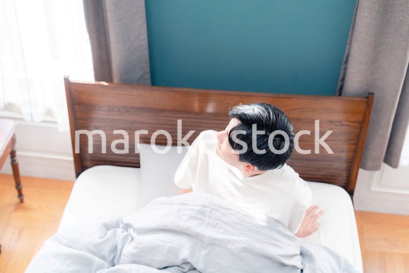 朝日が差し込む中で爽やかに目覚める若い男性