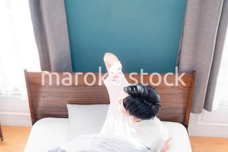 朝日が差し込む中で爽やかに目覚める若い男性