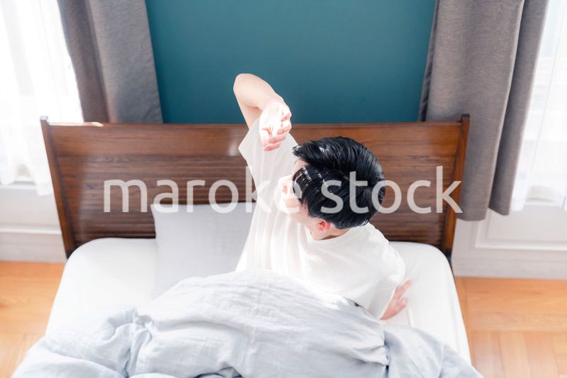 朝日が差し込む中で爽やかに目覚める若い男性