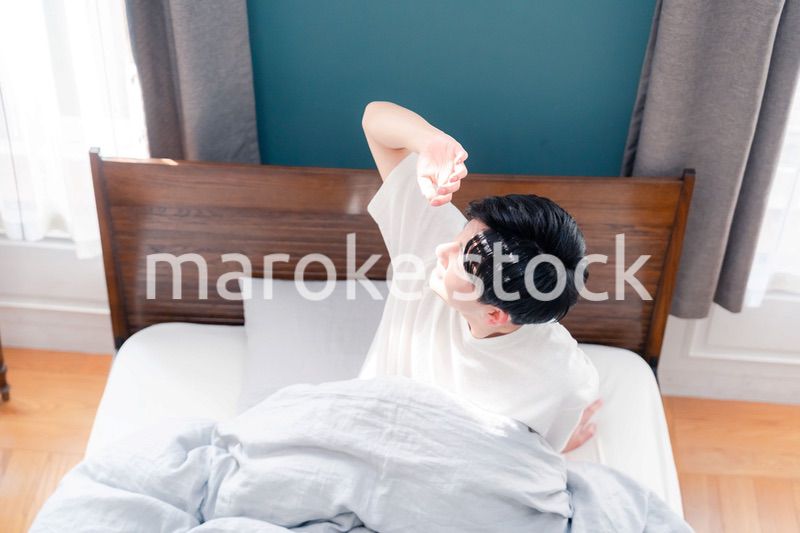 朝日が差し込む中で爽やかに目覚める若い男性