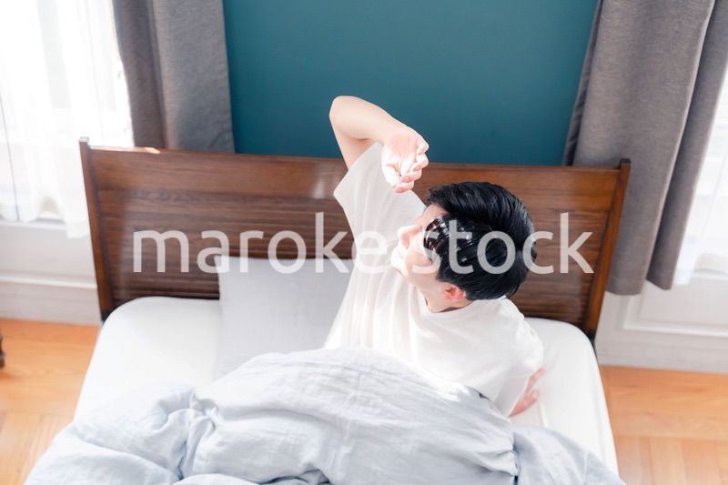 朝日が差し込む中で爽やかに目覚める若い男性