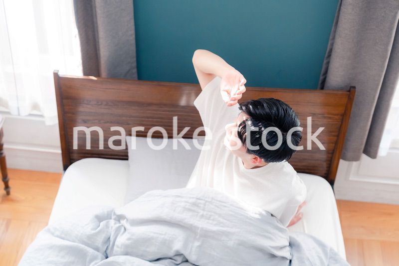 朝日が差し込む中で爽やかに目覚める若い男性