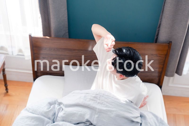 朝日が差し込む中で爽やかに目覚める若い男性