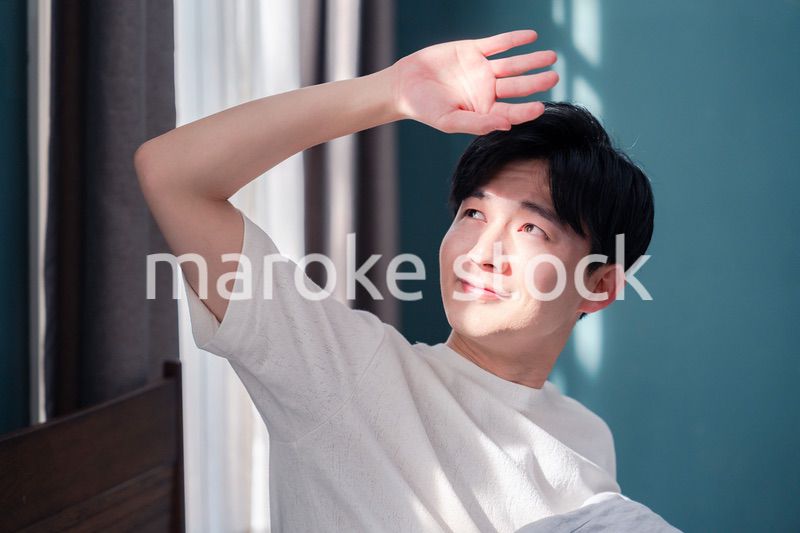 朝日が差し込む中で爽やかに目覚める若い男性