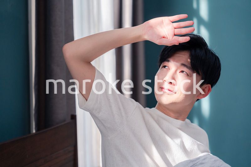 朝日が差し込む中で爽やかに目覚める若い男性