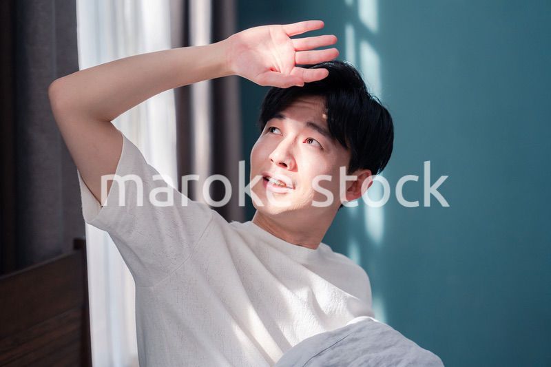 朝日が差し込む中で爽やかに目覚める若い男性