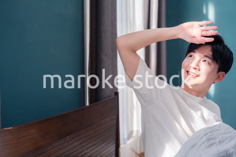 朝日が差し込む中で爽やかに目覚める若い男性