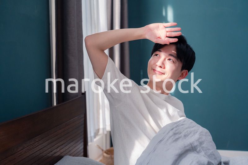 朝日が差し込む中で爽やかに目覚める若い男性