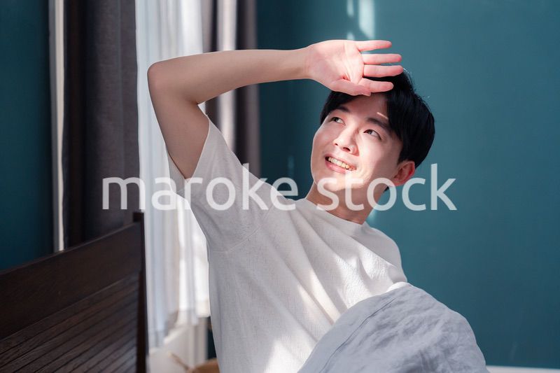 朝日が差し込む中で爽やかに目覚める若い男性