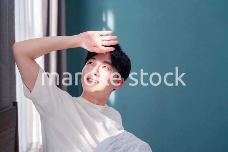 朝日が差し込む中で爽やかに目覚める若い男性