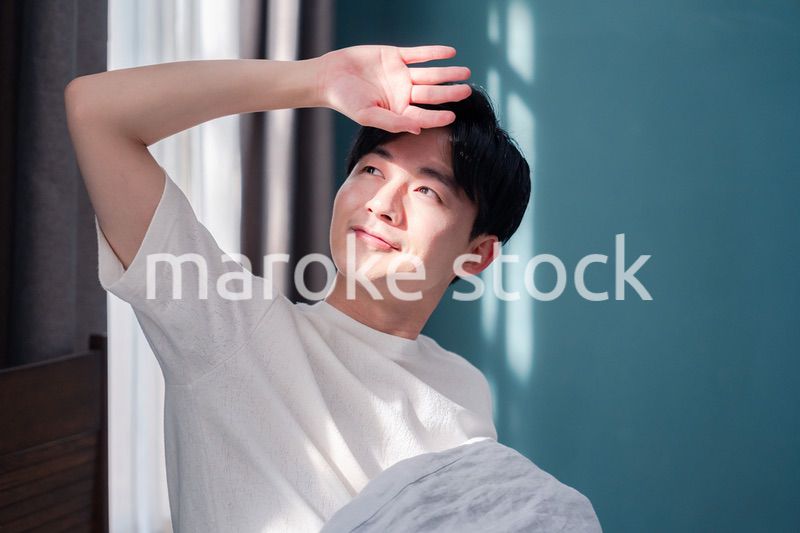 朝日が差し込む中で爽やかに目覚める若い男性
