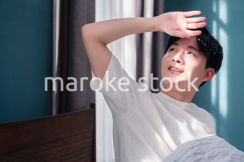 朝日が差し込む中で爽やかに目覚める若い男性