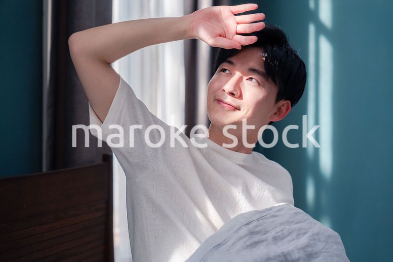 朝日が差し込む中で爽やかに目覚める若い男性