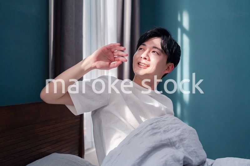 朝日が差し込む中で爽やかに目覚める若い男性